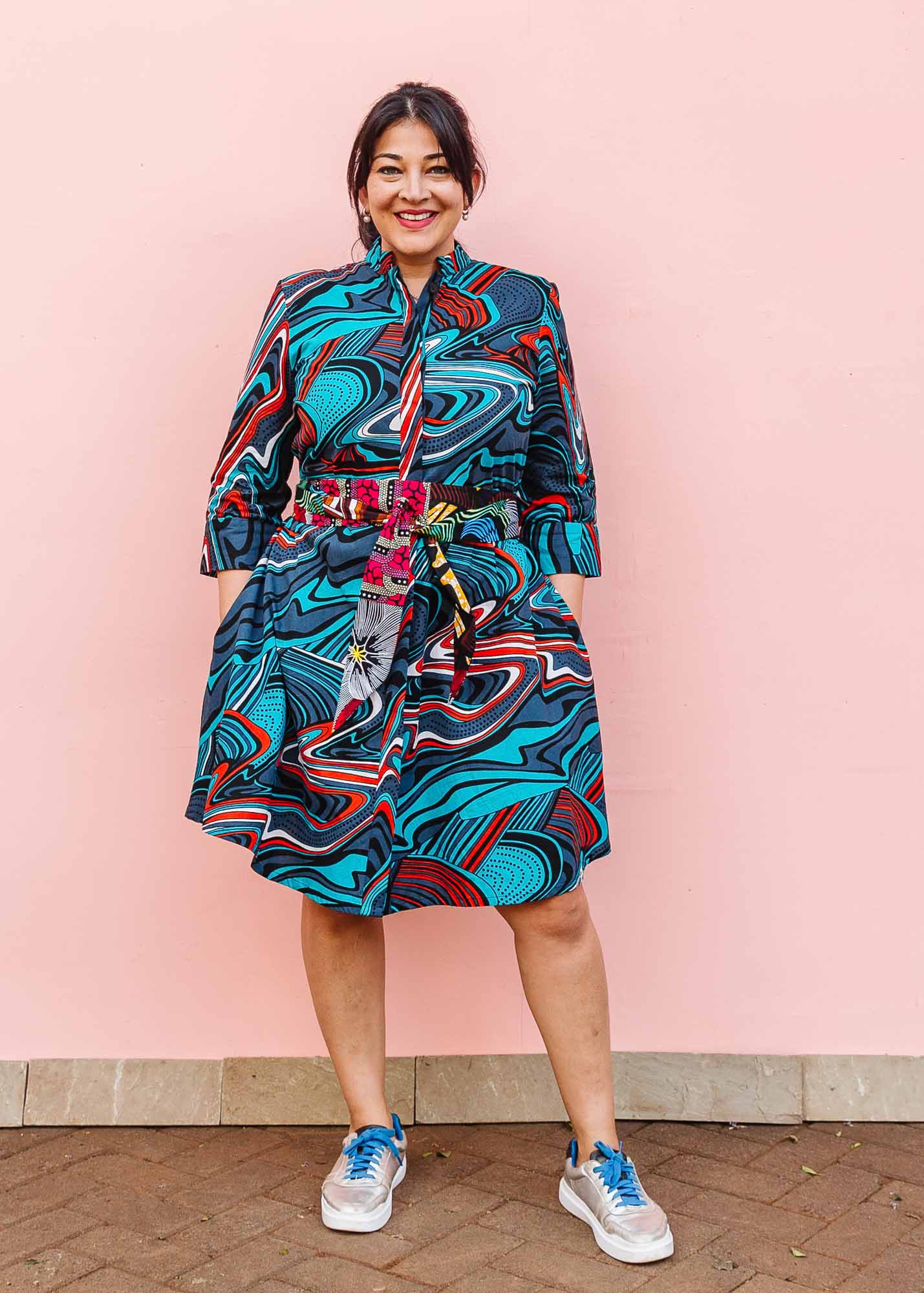The model is wearing turquoise, black, slate, white and red abstract print dress
