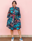 The model is wearing turquoise, black, slate, white and red abstract print dress