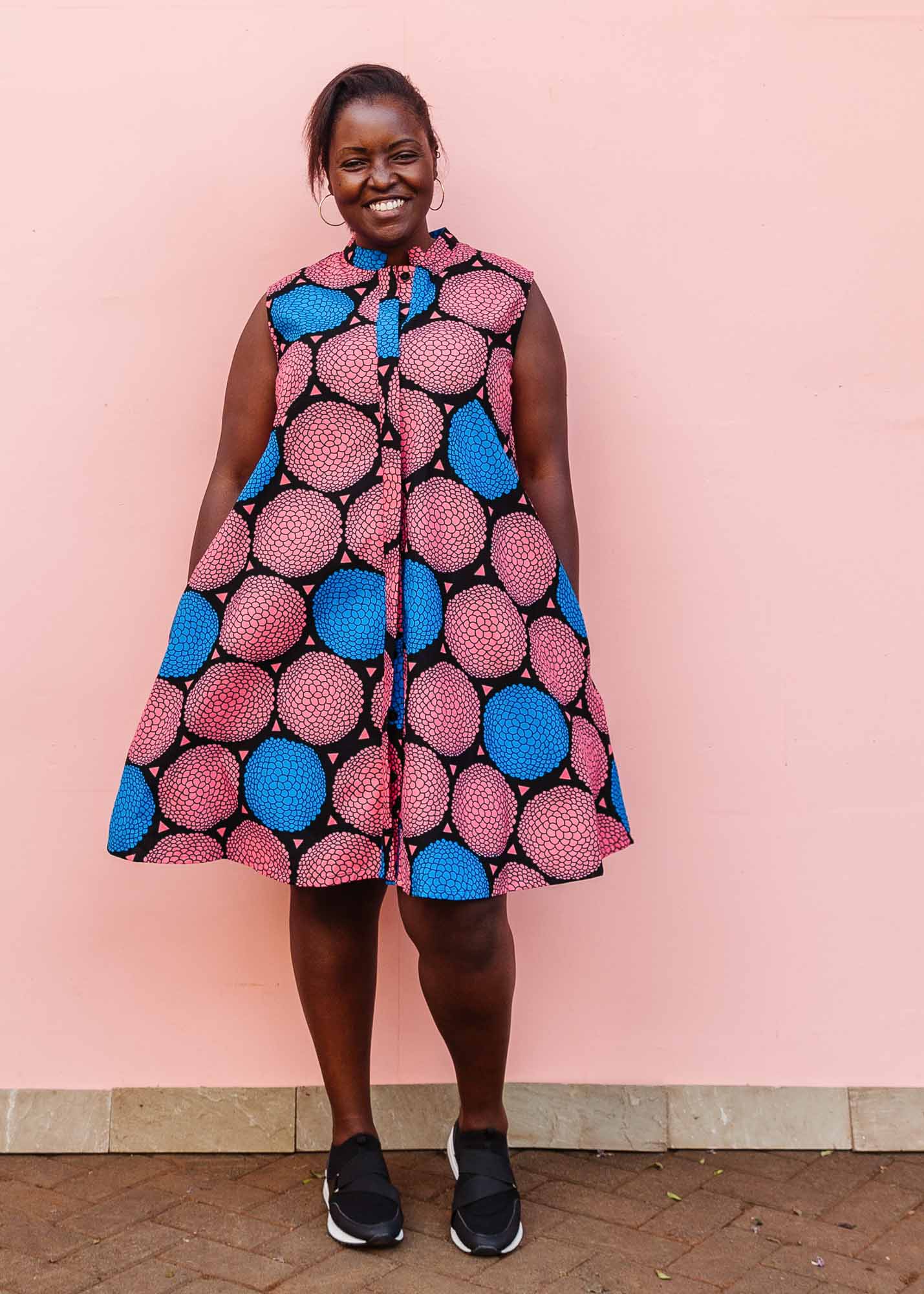 The model is wearing coral, blue and black circular print dress