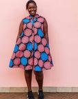 The model is wearing coral, blue and black circular print dress