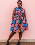 The model is wearing coral, blue and black circular print dress