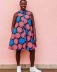 The model is wearing coral, blue and black circular print dress