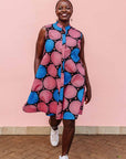The model is wearing coral, blue and black circular print dress