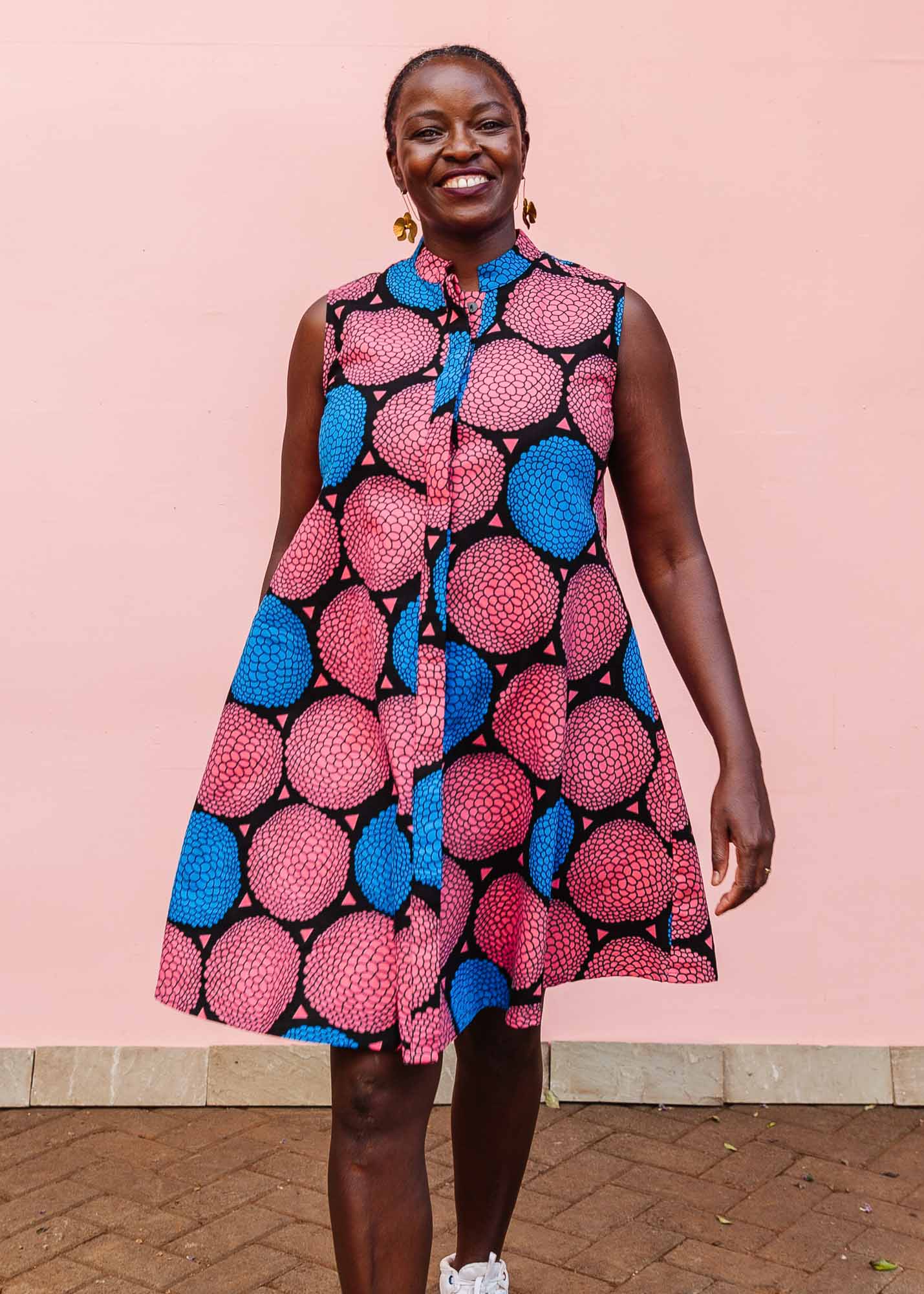 The model is wearing coral, blue and black circular print dress
