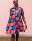 The model is wearing coral, blue and black circular print dress