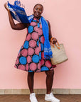 The model is wearing coral, blue and black circular print dress