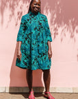 The model is wearing black, blue, green print dress