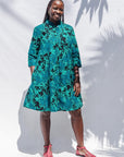 The model is wearing black, blue, green print dress