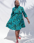 The model is wearing black, blue, green print dress