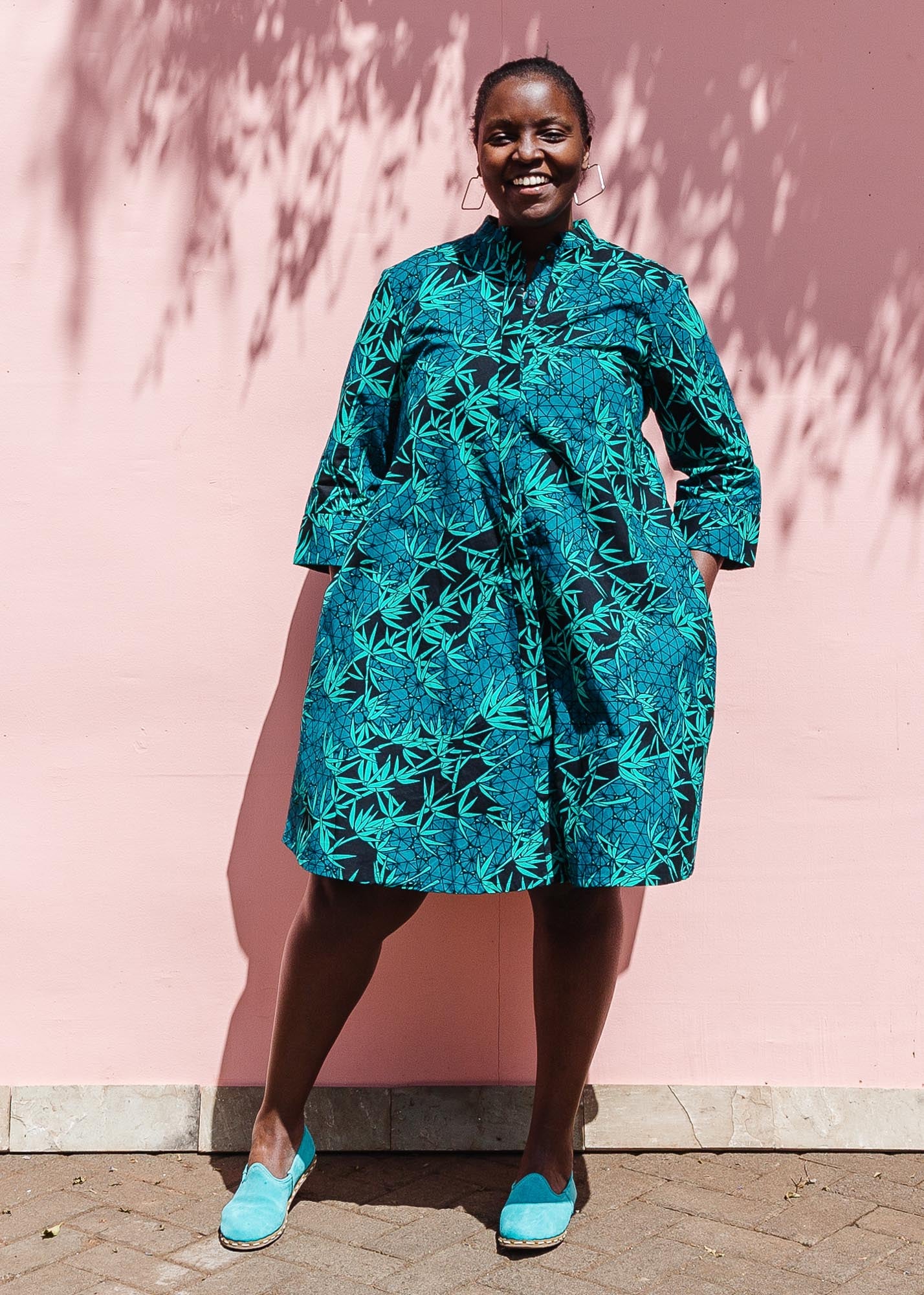 The model is wearing black, blue,  green print dress