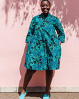 The model is wearing black, blue, green print dress
