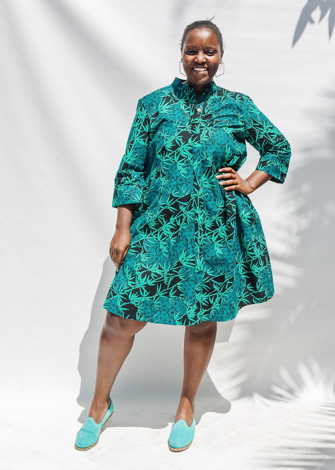 The model is wearing black, blue,  green print dress