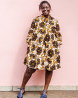 The model is wearing navy, black, off white, yellow flower print dress