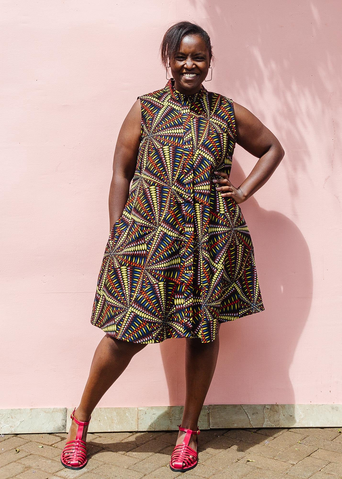 The model is wearing multi-colored abstract print dress
