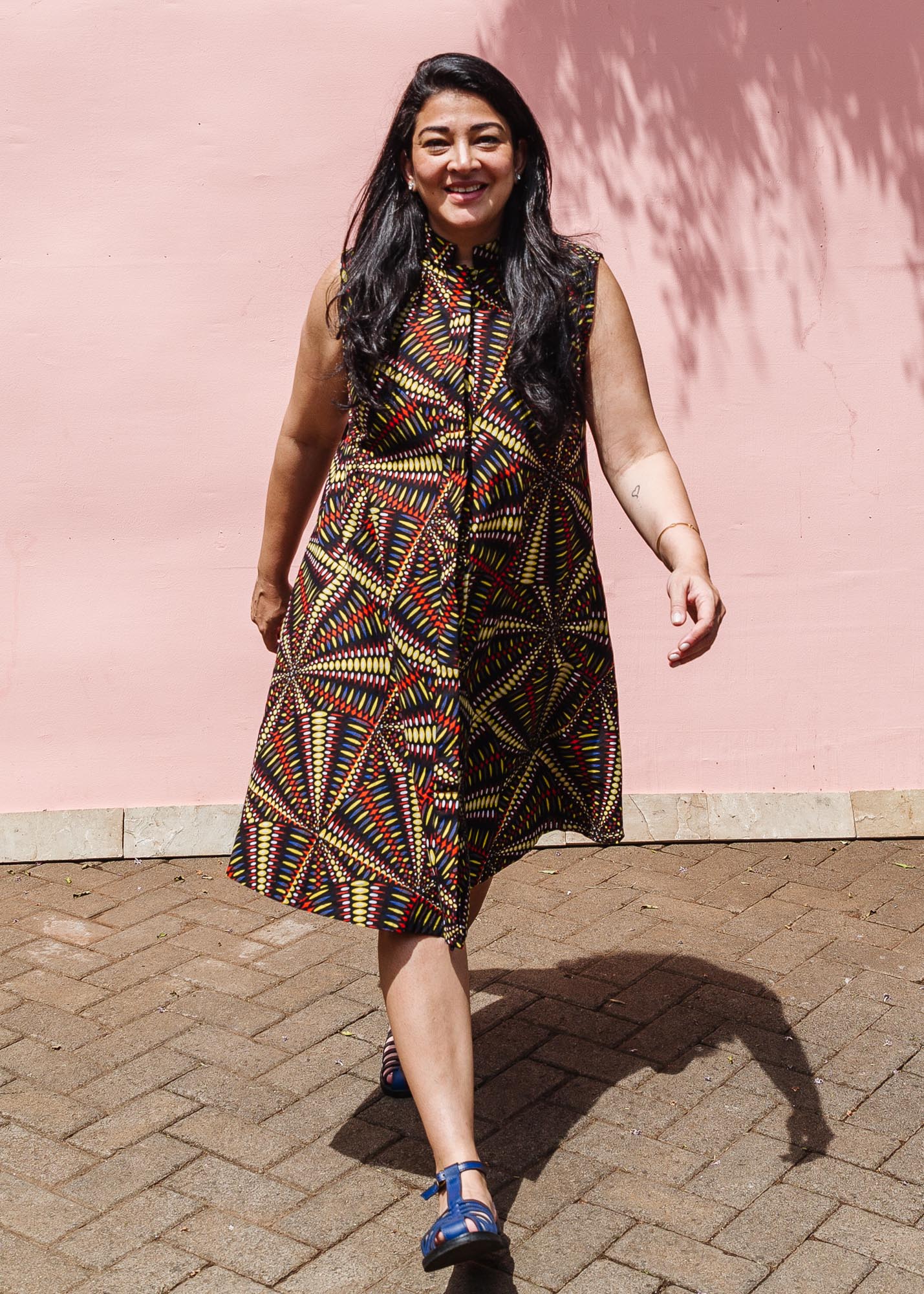 The model is wearing multi-colored abstract print dress