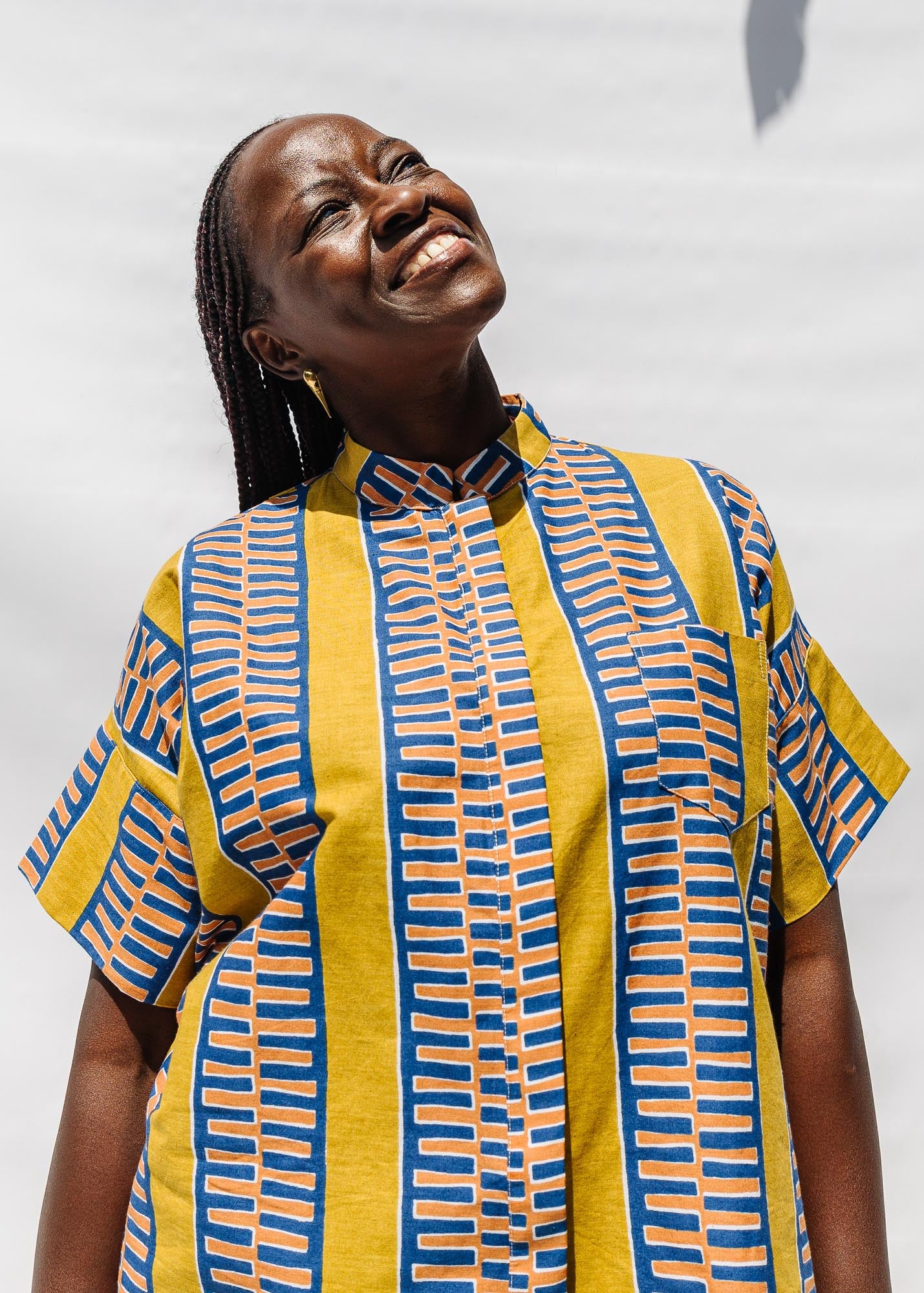 The model is wearing olive-yellow, blue, orange and white geometric printed shirt