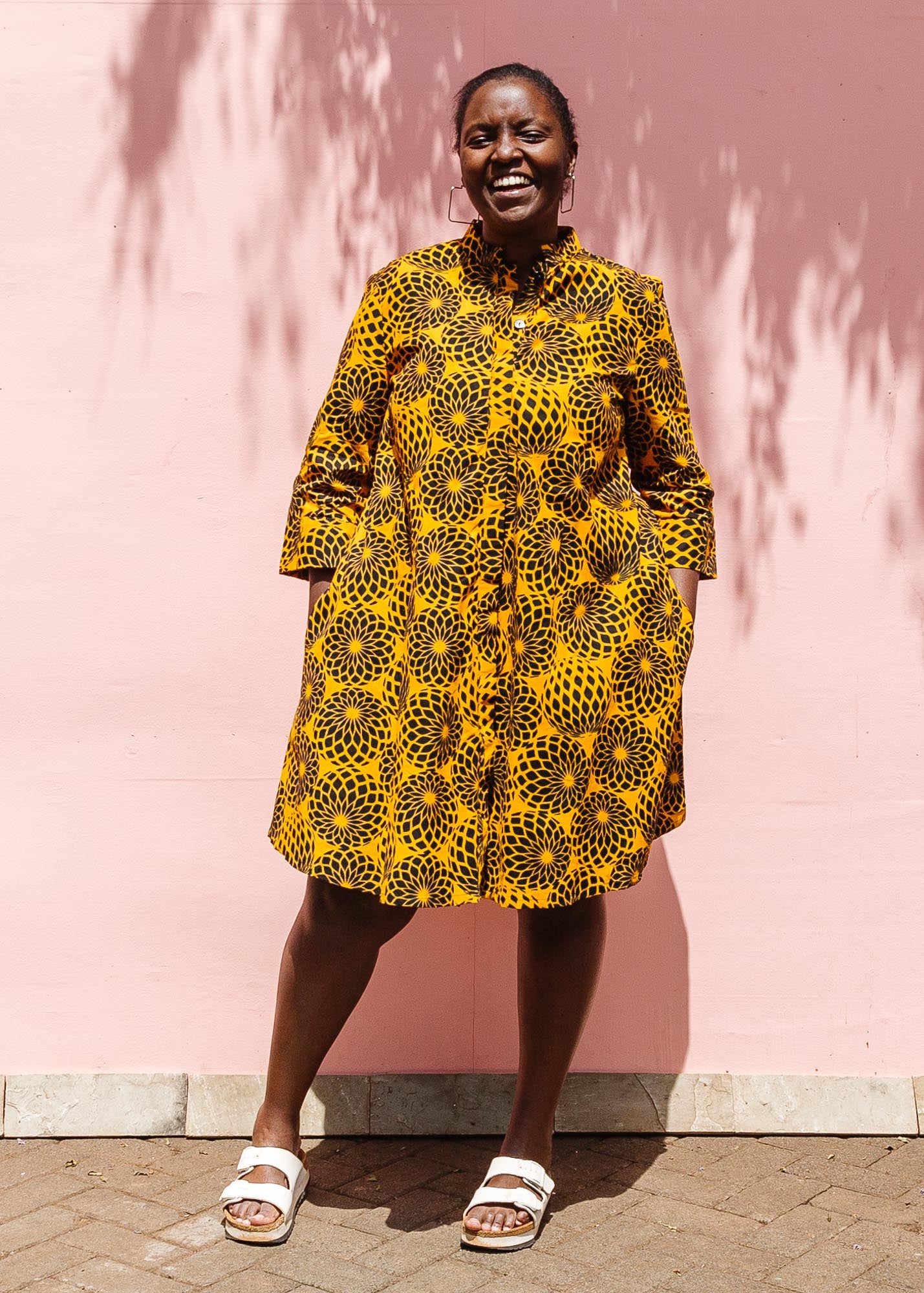 The model is wearing black, yellow print dress