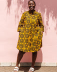 The model is wearing black, yellow print dress