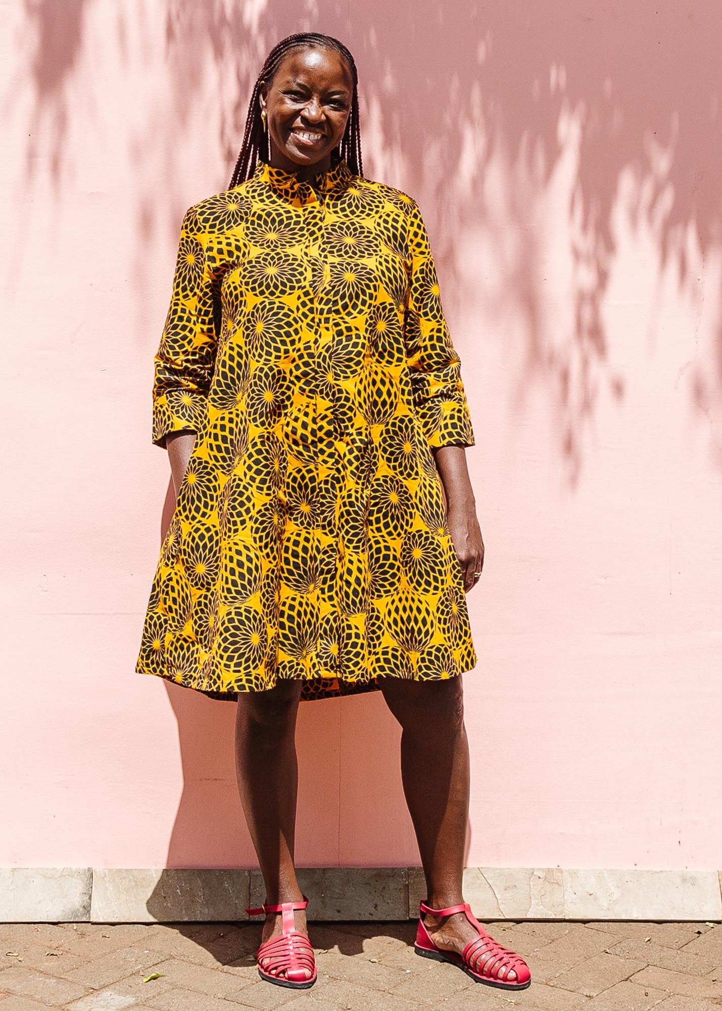 The model is wearing black, yellow print dress