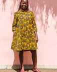 The model is wearing black, yellow print dress