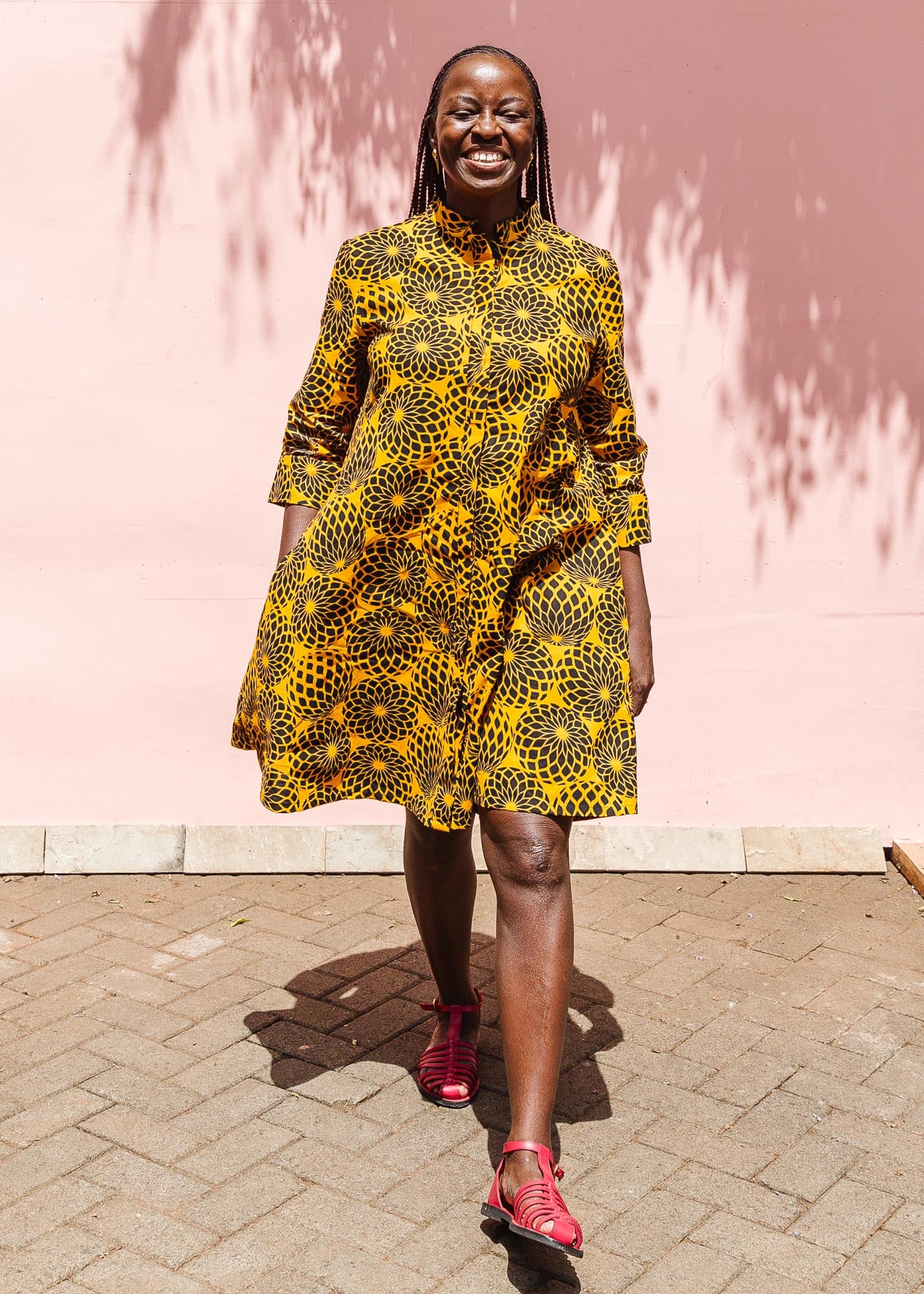 The model is wearing black, yellow print dress
