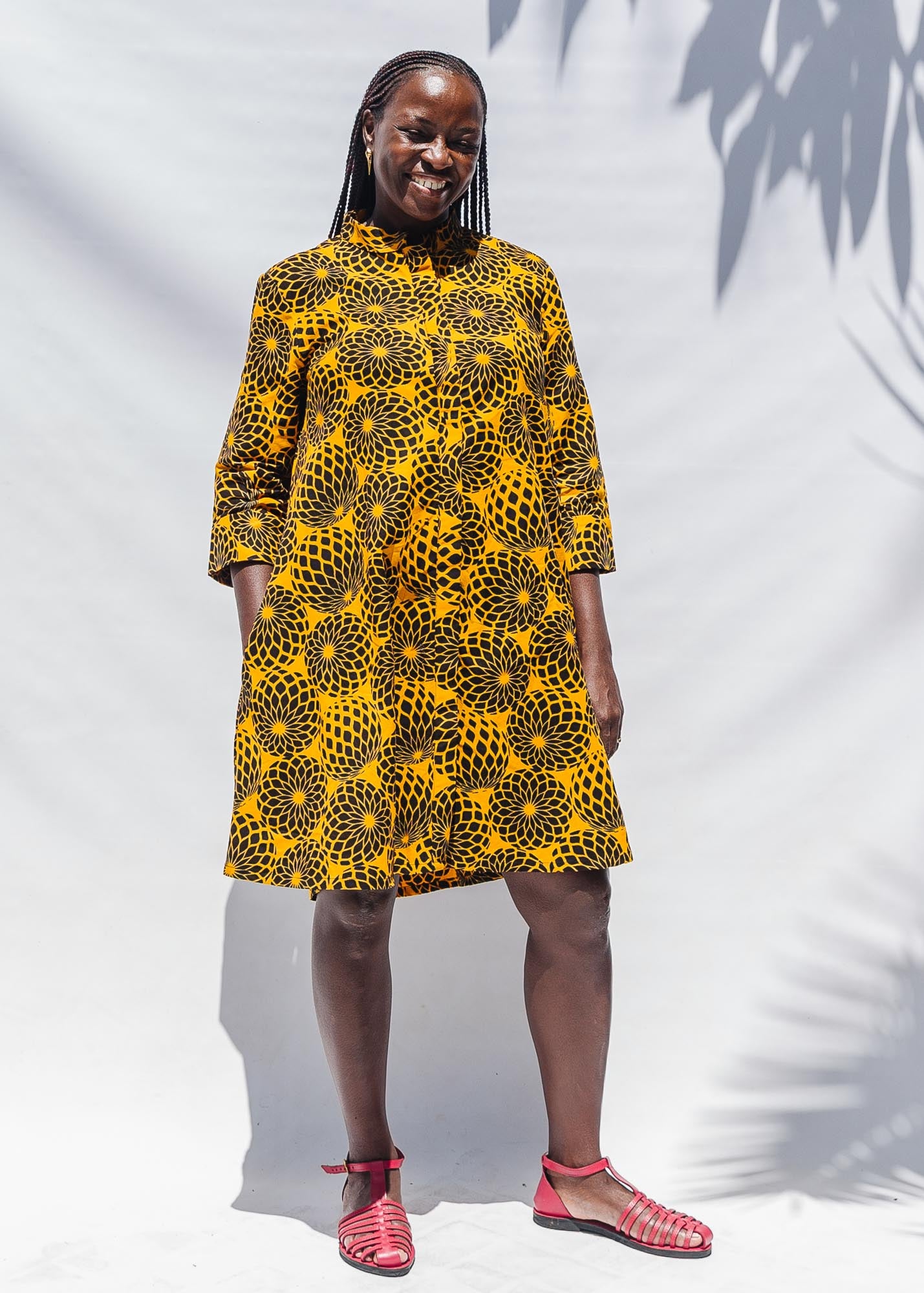 The model is wearing black, yellow print dress