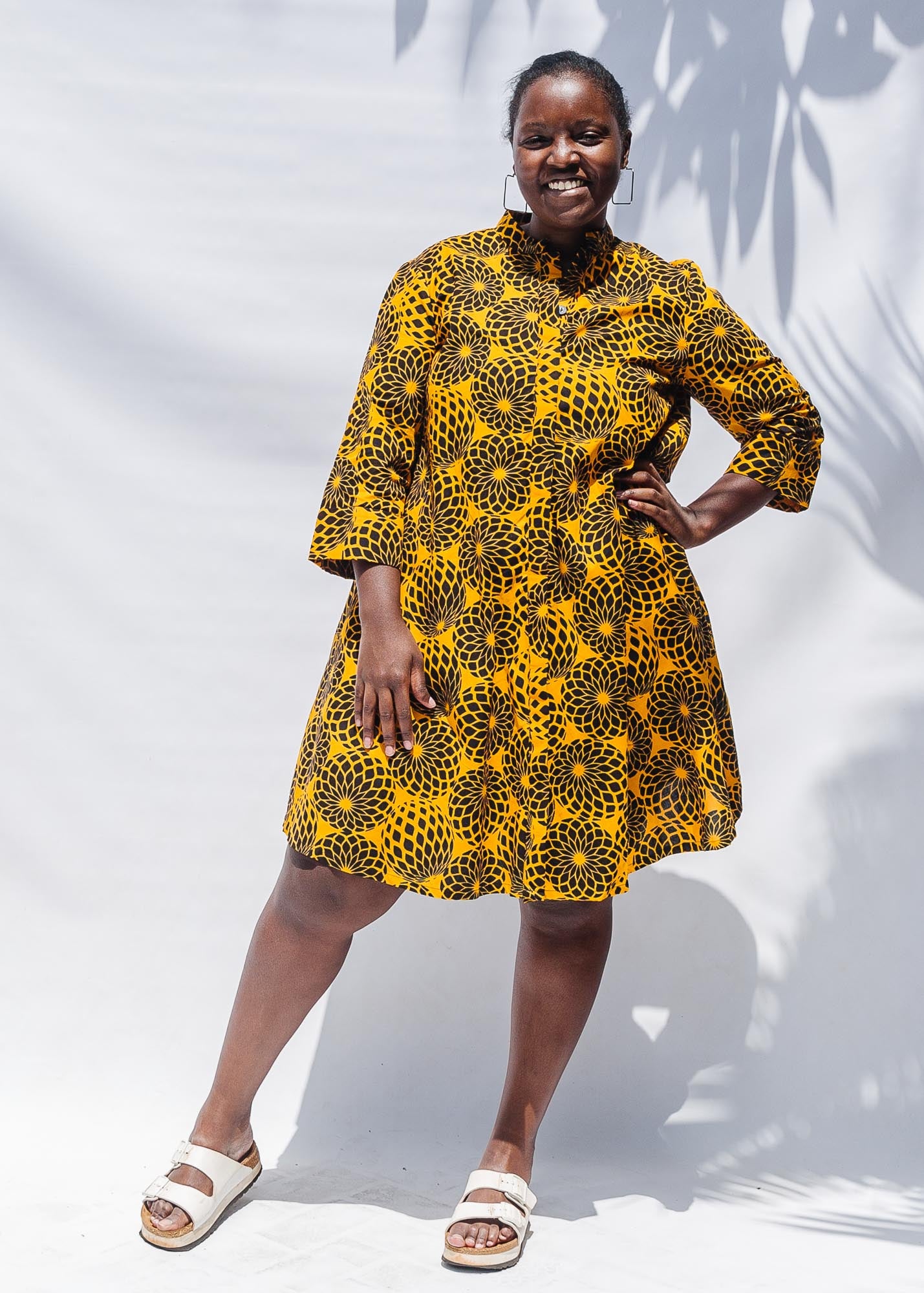 The model is wearing black, yellow print dress