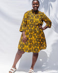 The model is wearing black, yellow print dress