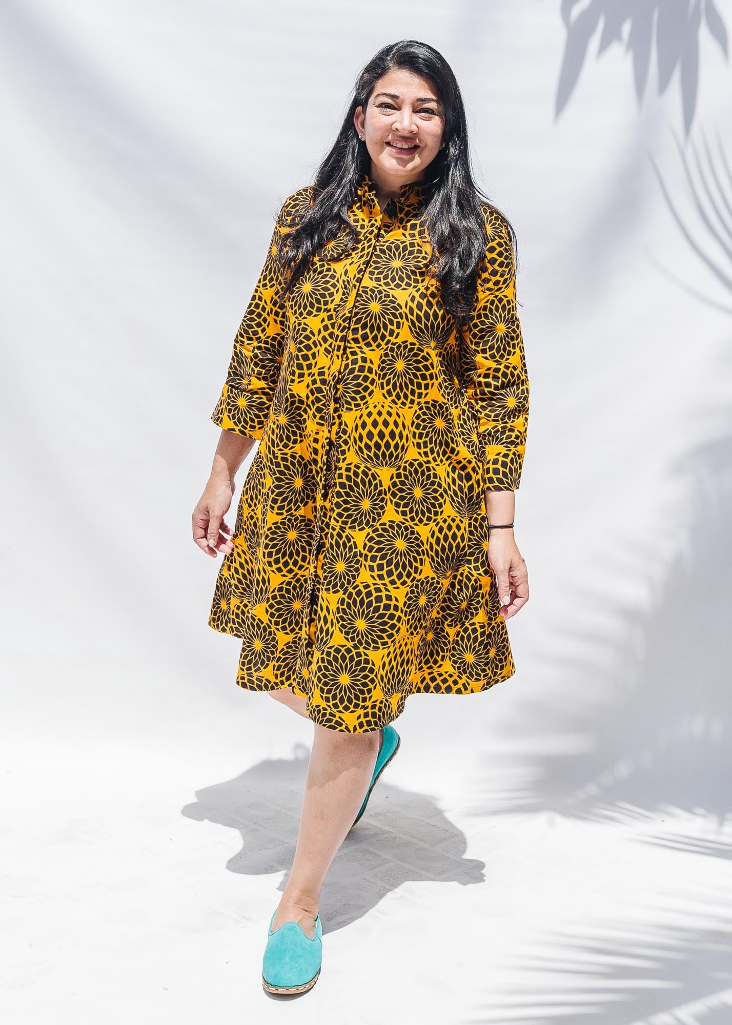 The model is wearing black, yellow print dress