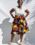 The model is wearing black, white, red, yellow, peach floral print dress