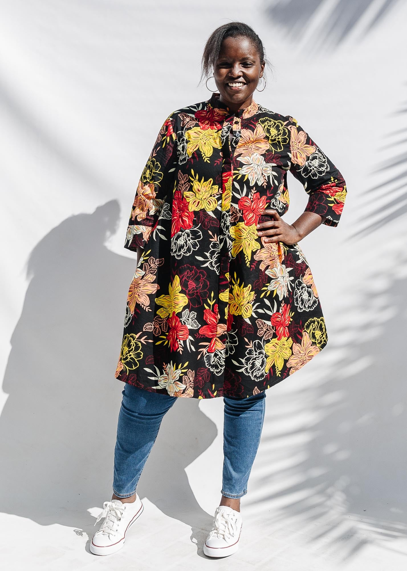 The model is wearing black, white, red, yellow, peach floral print dress