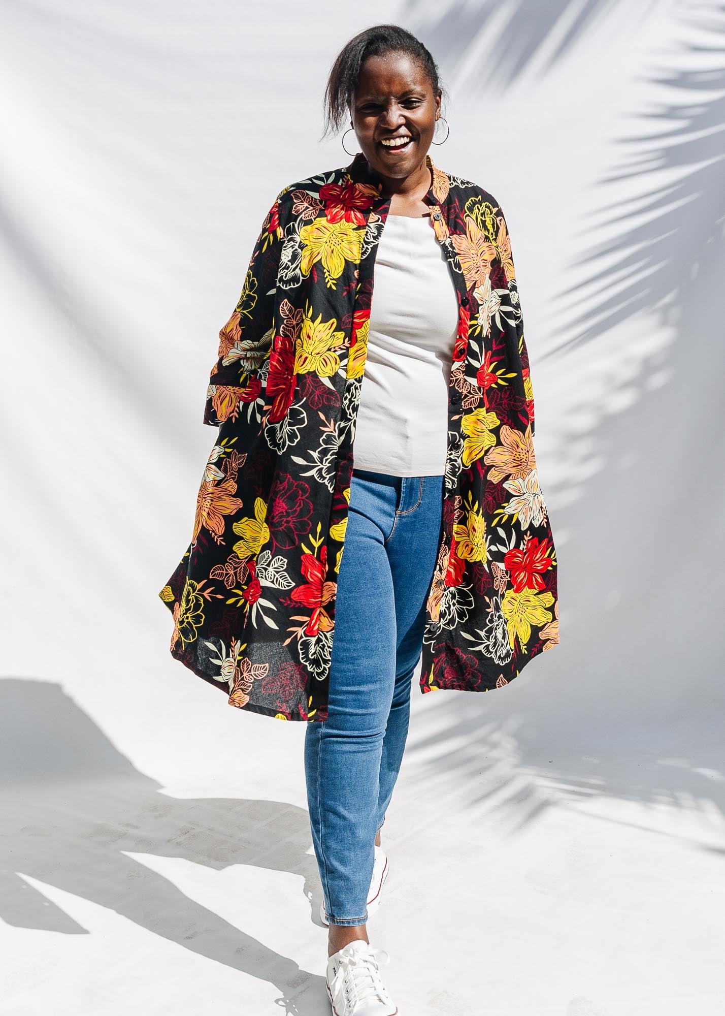 The model is wearing black, white, red, yellow, peach floral print dress