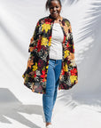 The model is wearing black, white, red, yellow, peach floral print dress