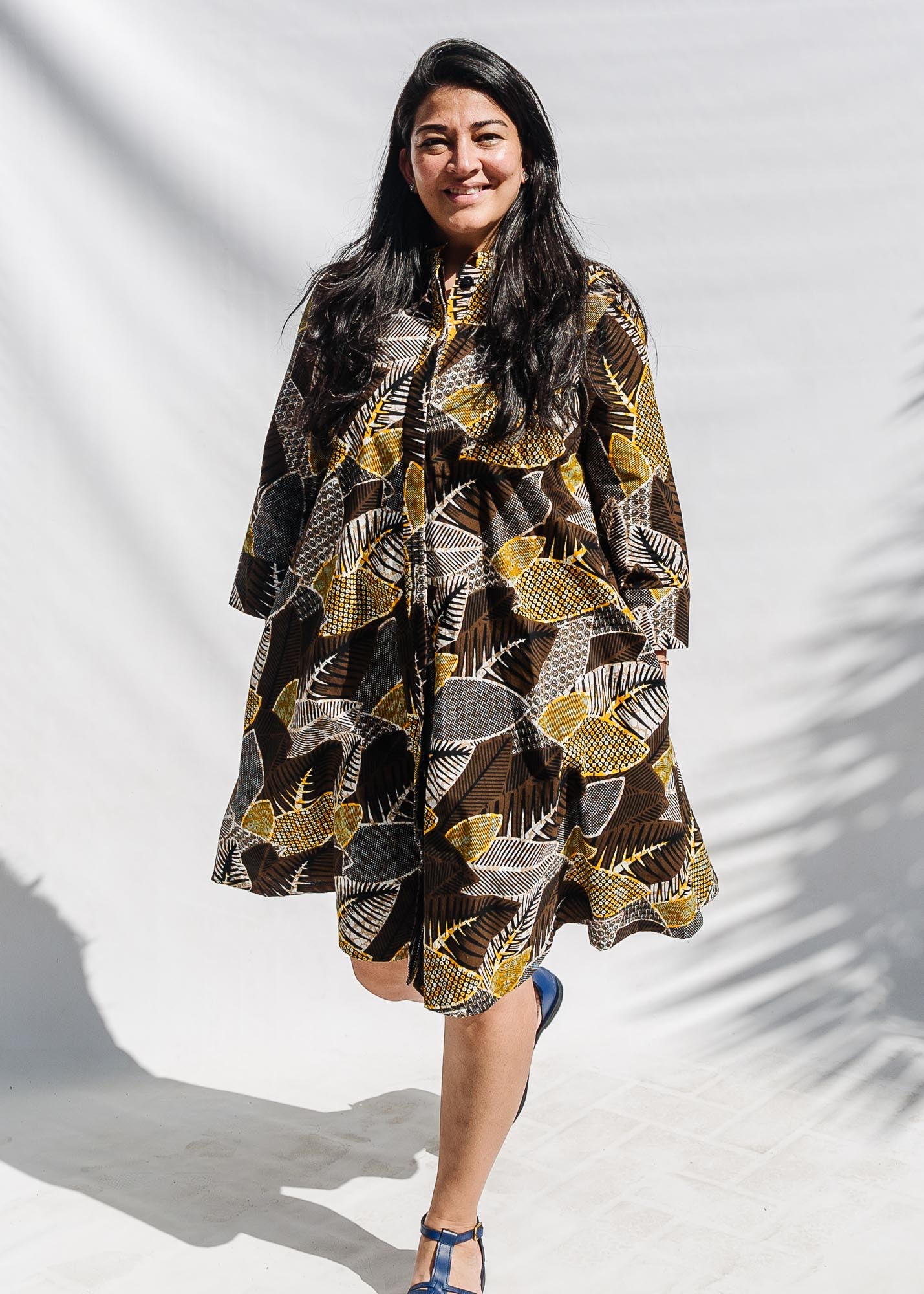 The model is wearing black, brown, yellow, beige print dress