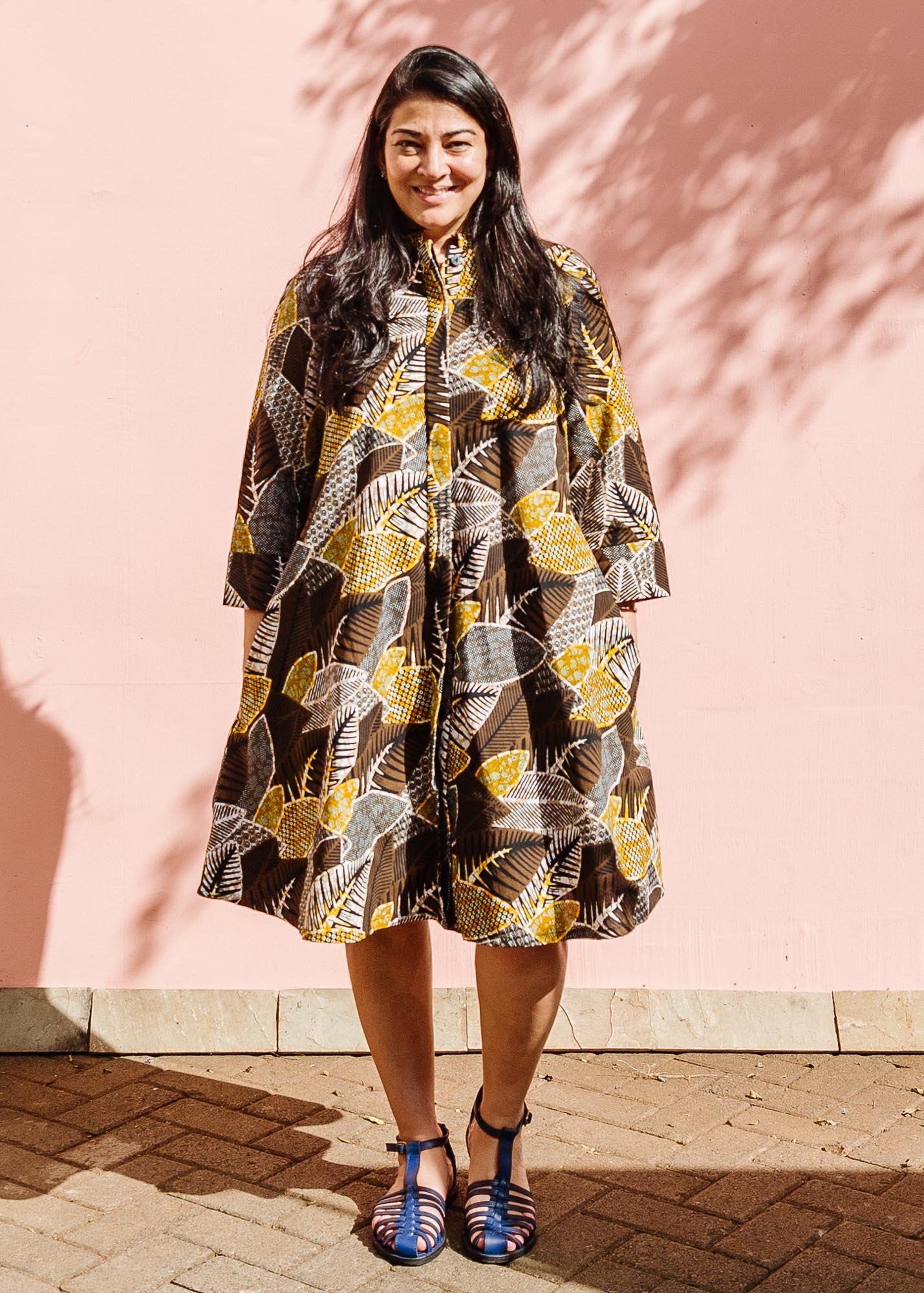 The model is wearing black, brown, yellow, beige print dress