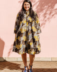 The model is wearing black, brown, yellow, beige print dress
