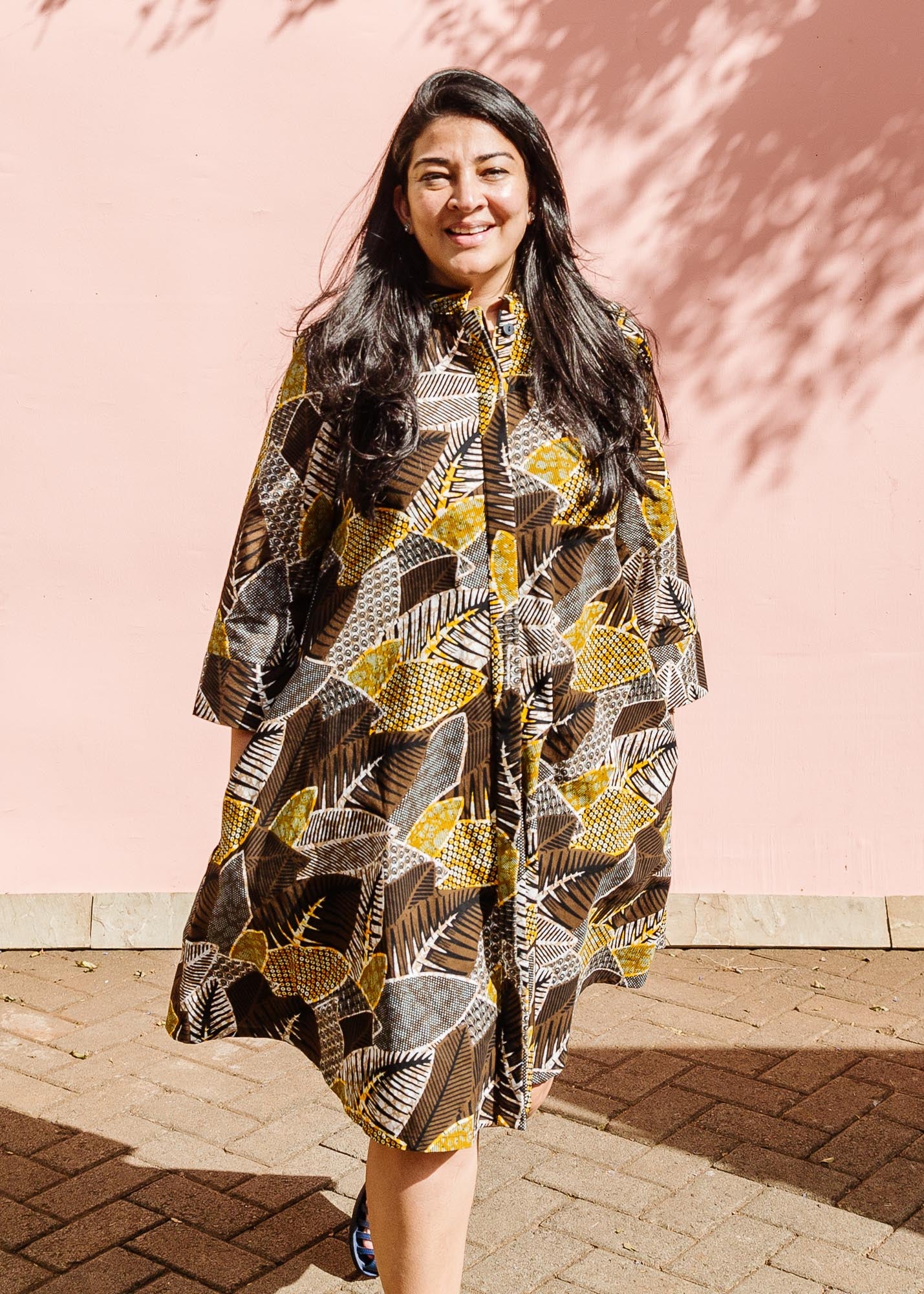 The model is wearing black, brown, yellow, beige print dress