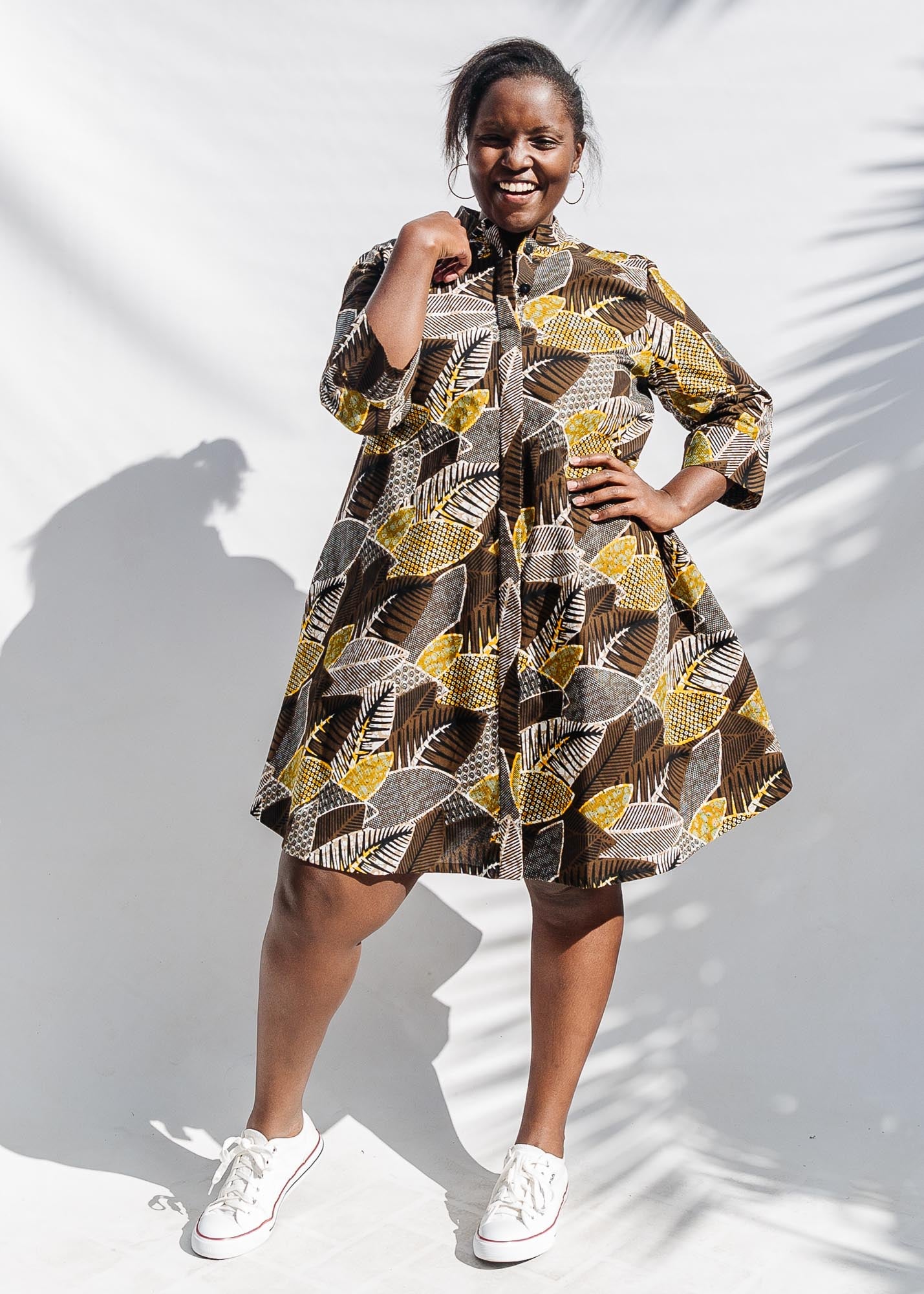 The model is wearing black, brown, yellow, beige print dress