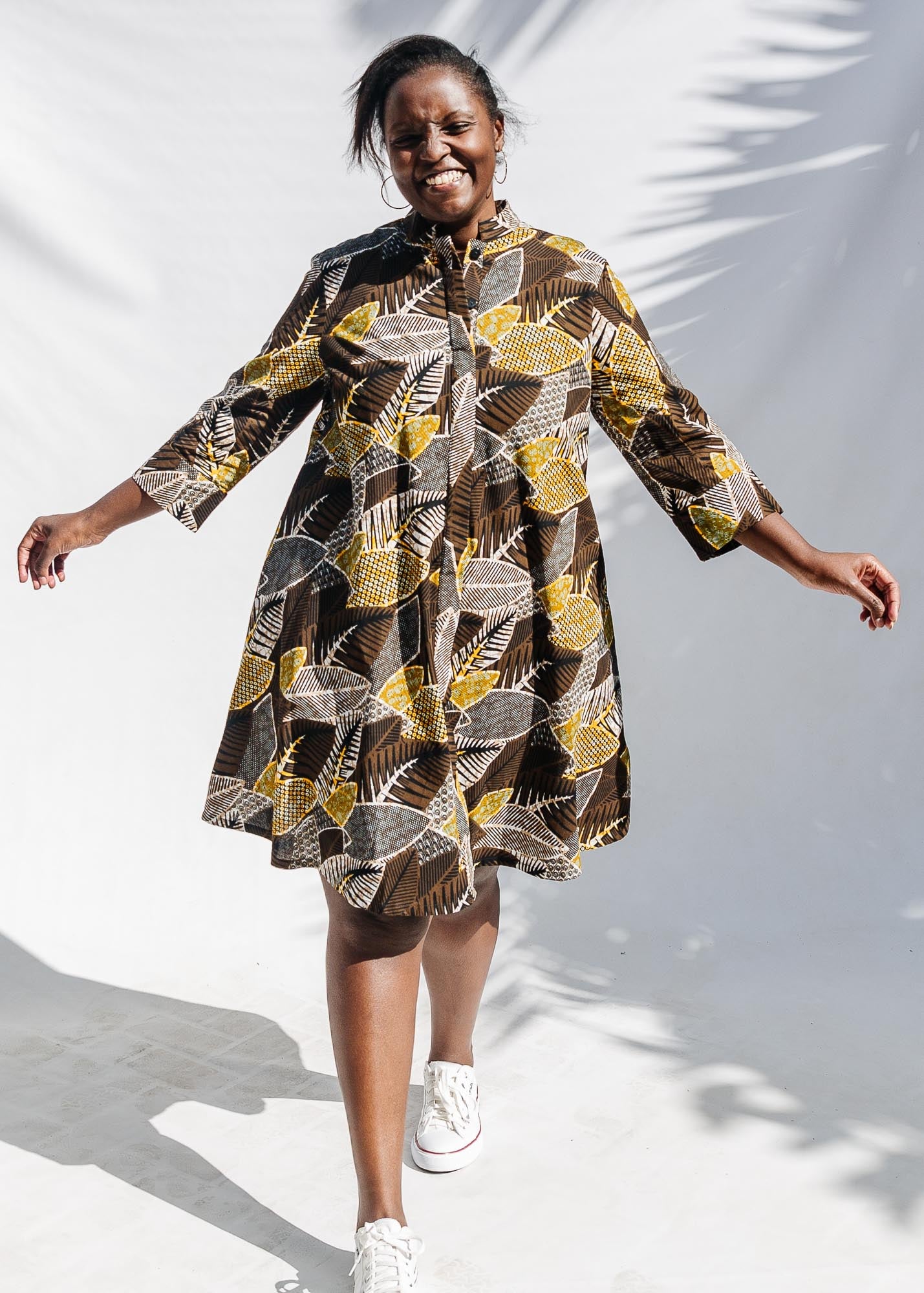 The model is wearing black, brown, yellow, beige print dress
