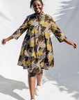 The model is wearing black, brown, yellow, beige print dress