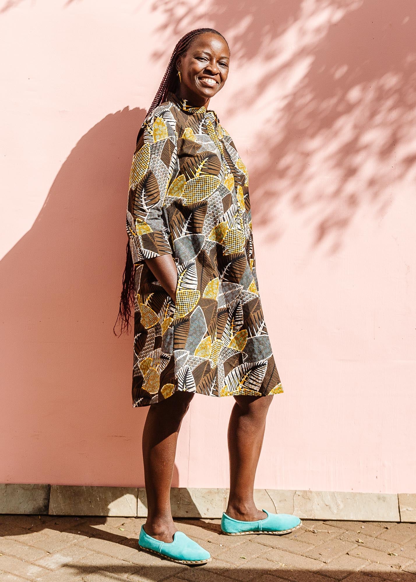 The model is wearing black, brown, yellow, beige print dress