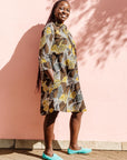 The model is wearing black, brown, yellow, beige print dress
