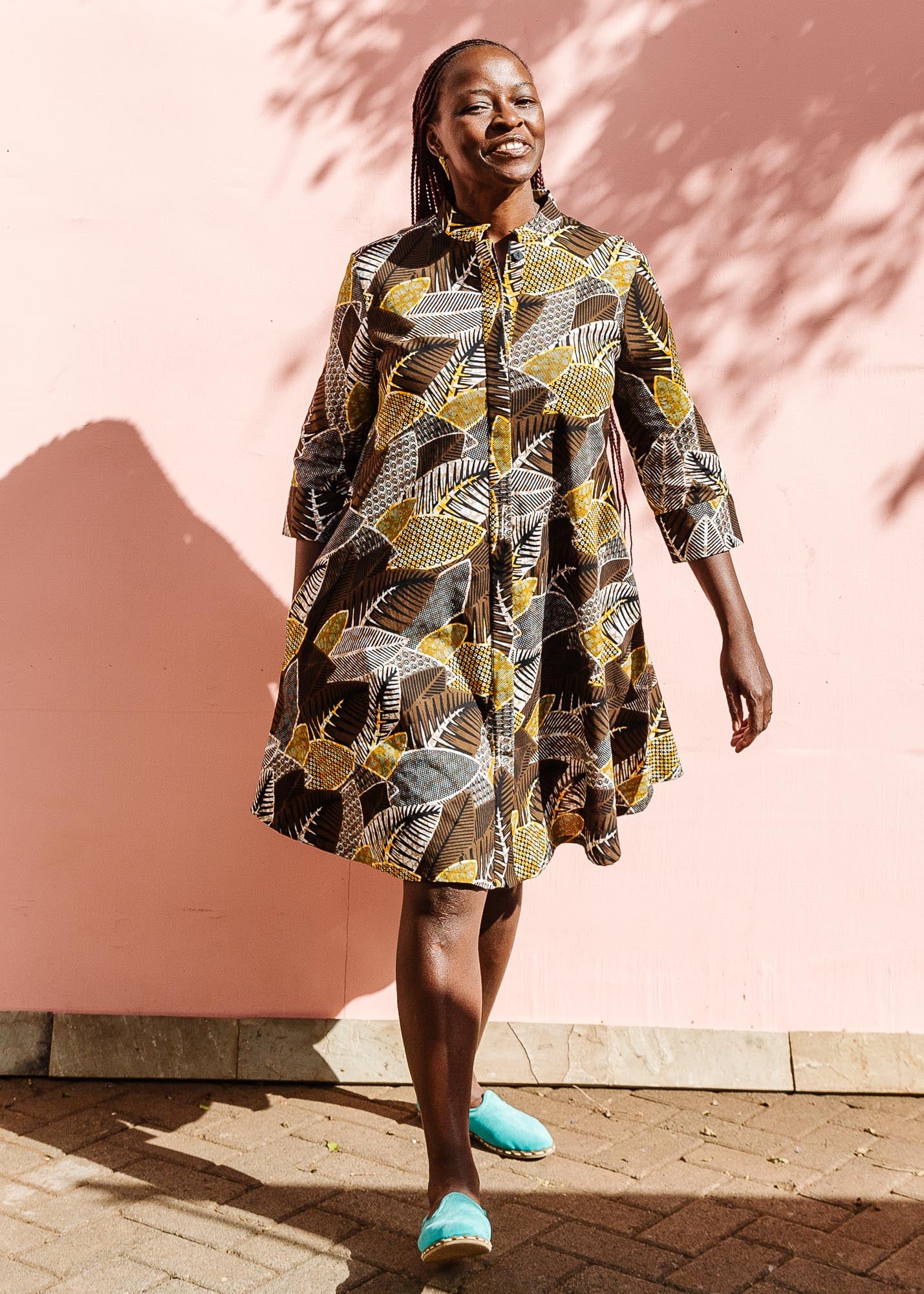 The model is wearing black, brown, yellow, beige print dress