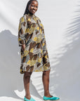 The model is wearing black, brown, yellow, beige print dress