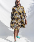 The model is wearing black, brown, yellow, beige print dress