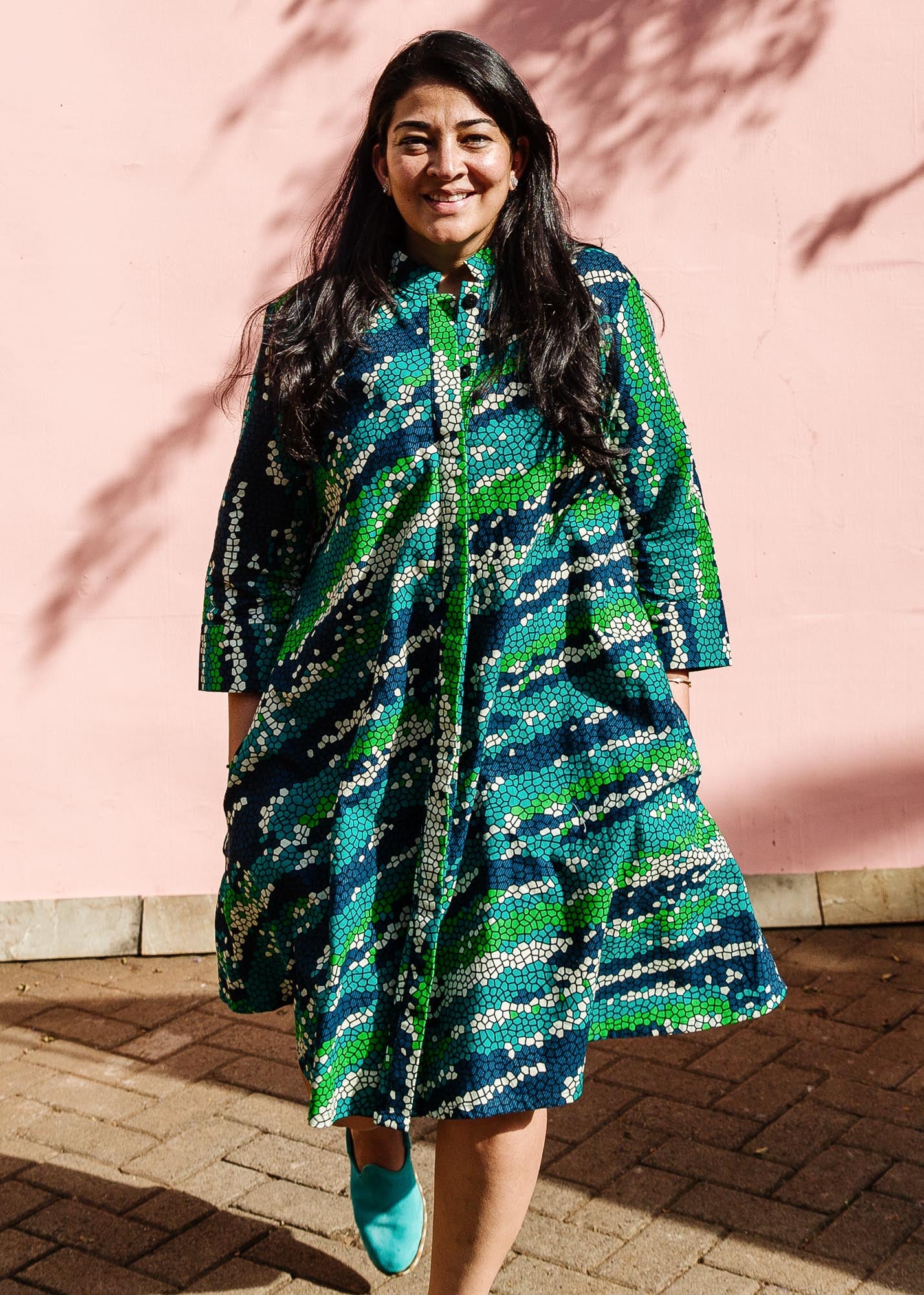 The model is wearing black, green, white, blue and aqua print dress