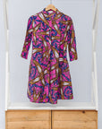 Display of pink dress with floral yellow, blue and white print.