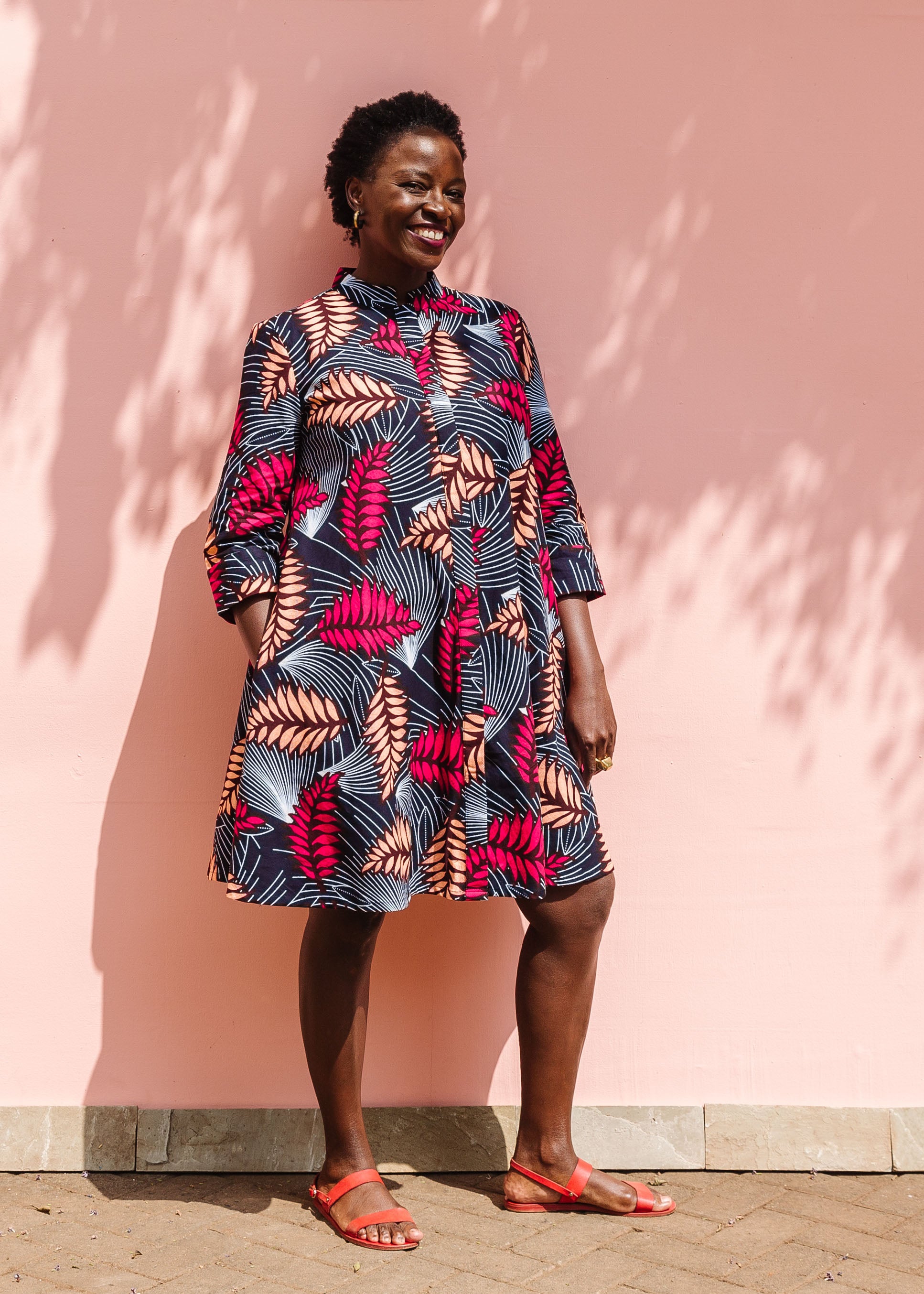 Model wearing a navy dress with red and peach feather print.