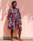 Model wearing a navy dress with red and peach feather print.