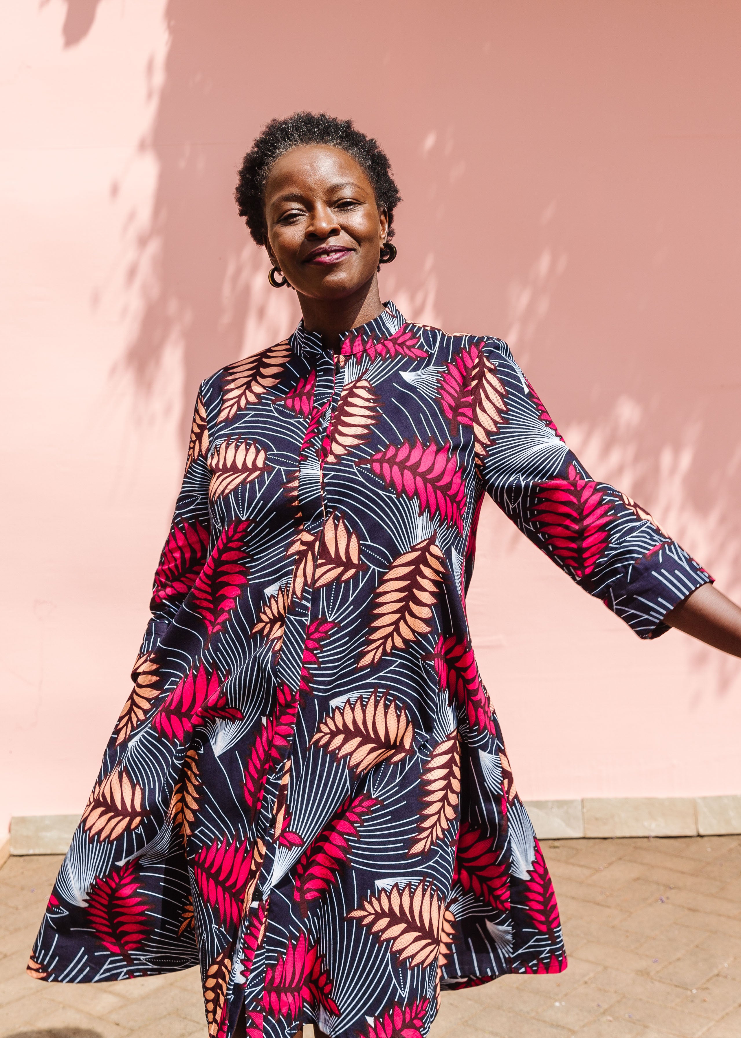 Model wearing a navy dress with red and peach feather print.